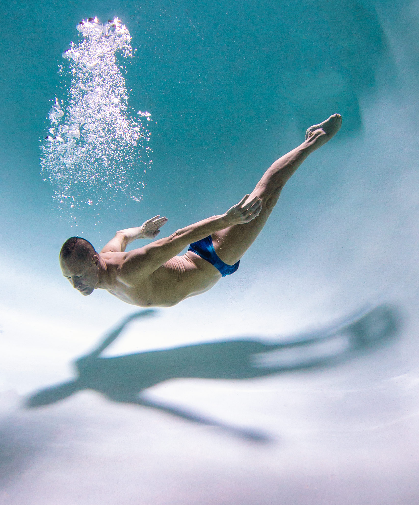 World champion synchronized swimmer floating towards the bottom of the pool. Underwater photography advertising . Bill May