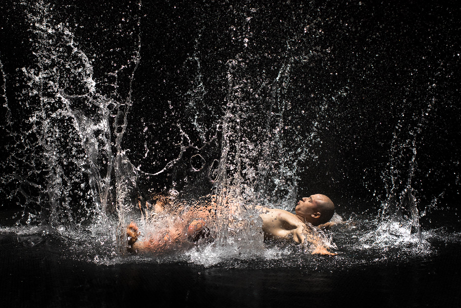 An acrobat hitting the water flat on his back. Water splash surrounding a man . Advertising photo for Le Rêve the show at Wynn Las Vegas. Cirque du Soleil